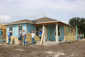 Habitat Orlando & Osceola volunteers attach siding to a home under construction.