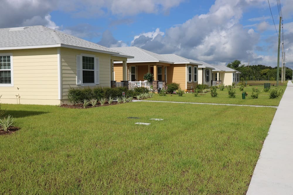 Row of yellow houses and front lawns in one of Habitat's communities for homeowners