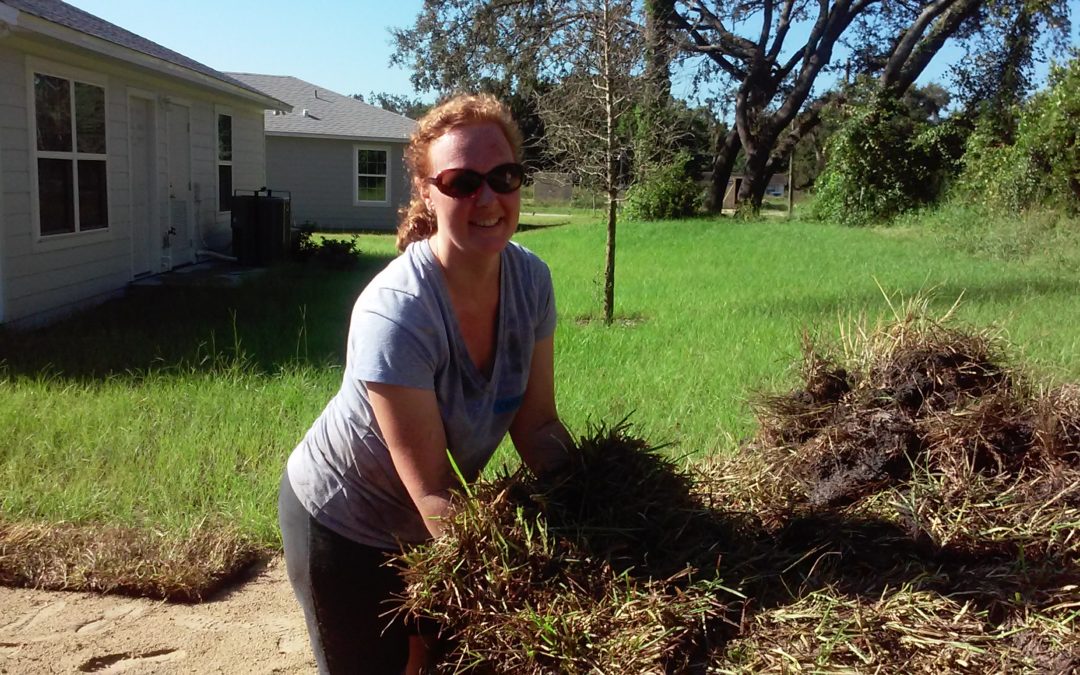 Woman smiling and holding sod to install behind house