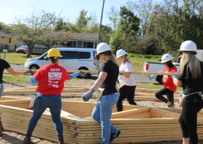 Group of women wearing hard hats and carrying trusses