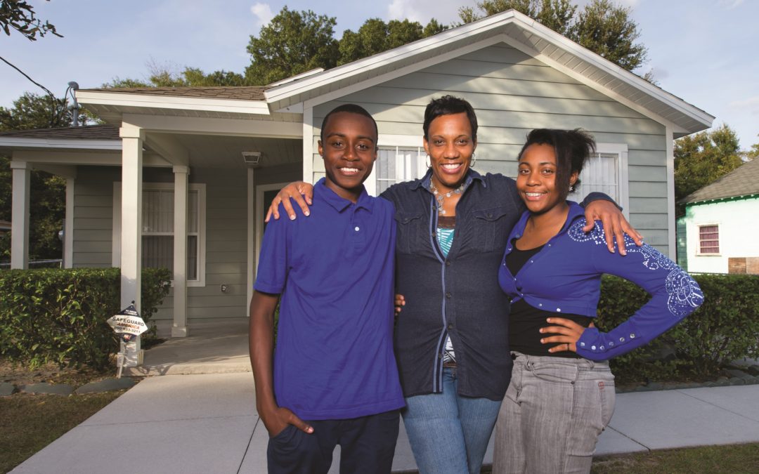 Woman with two teenage children in front of completed grey house