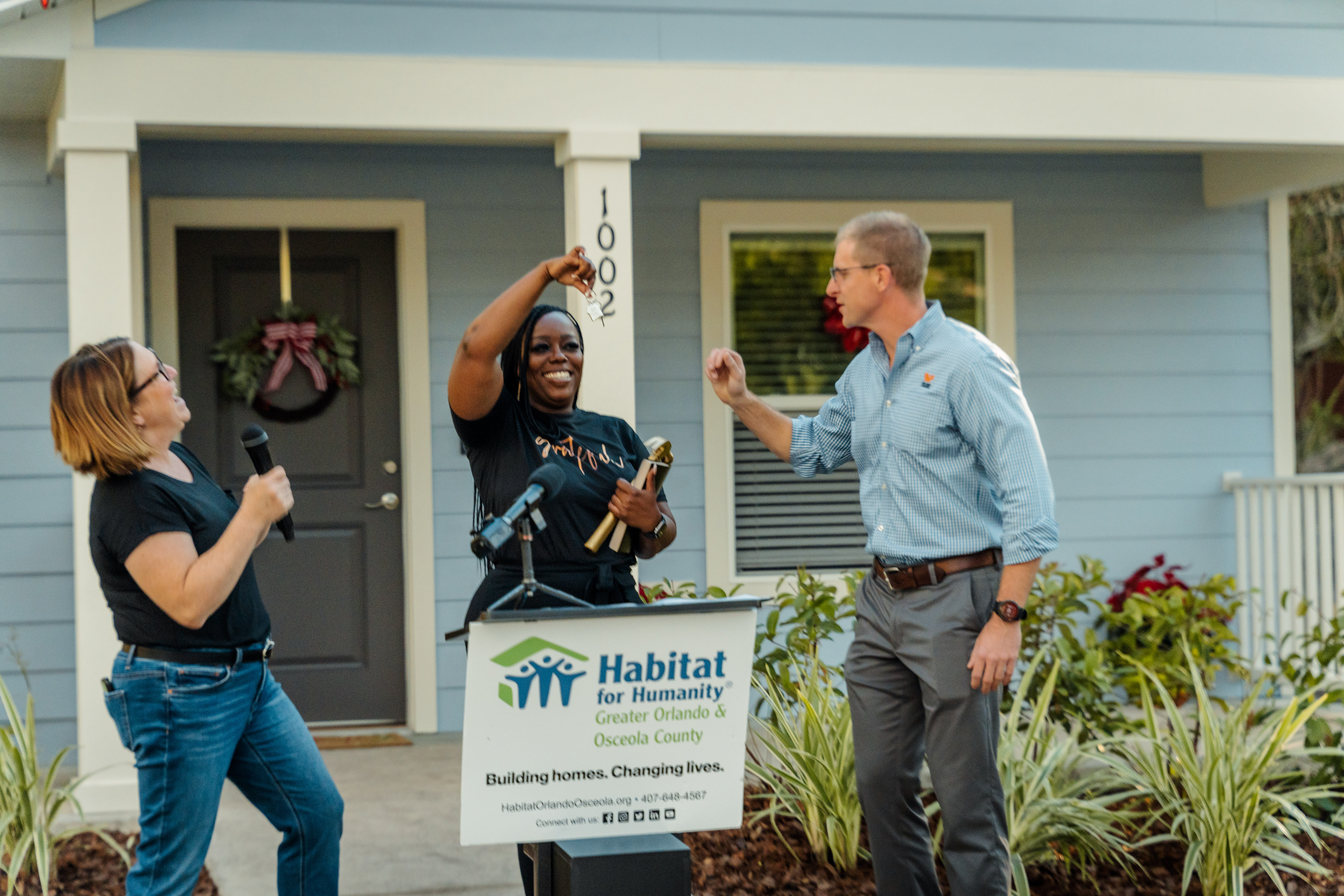 Woman smiling and reaching up to paint siding of house with text overlay "Women Build: A fundraising event" and Habitat Orlando & Osceola logo